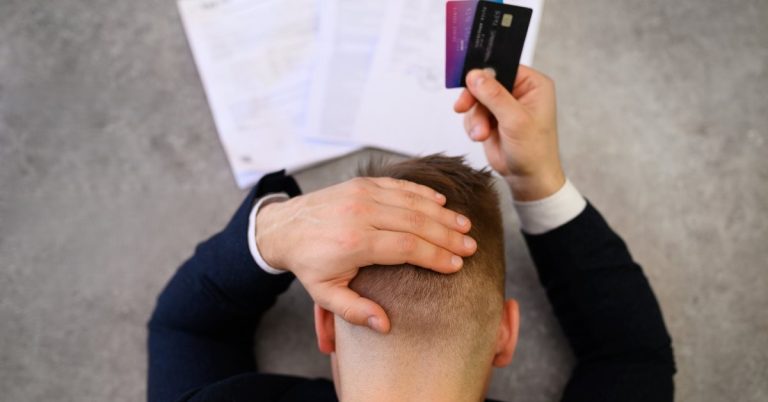 man stressed about credit card debt holding bills