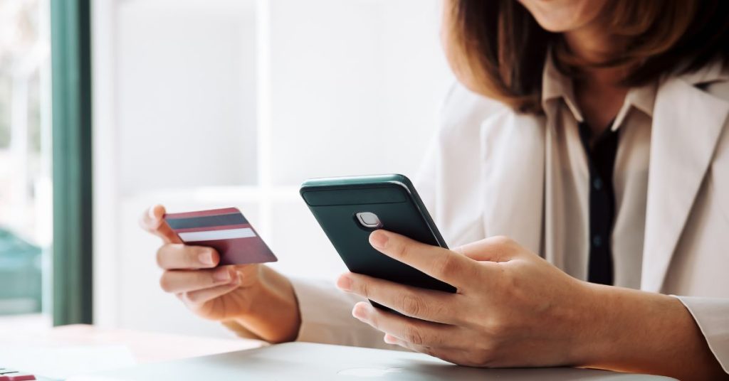 Woman managing credit card and phone — how to lower your credit utilization and improve your credit score fast