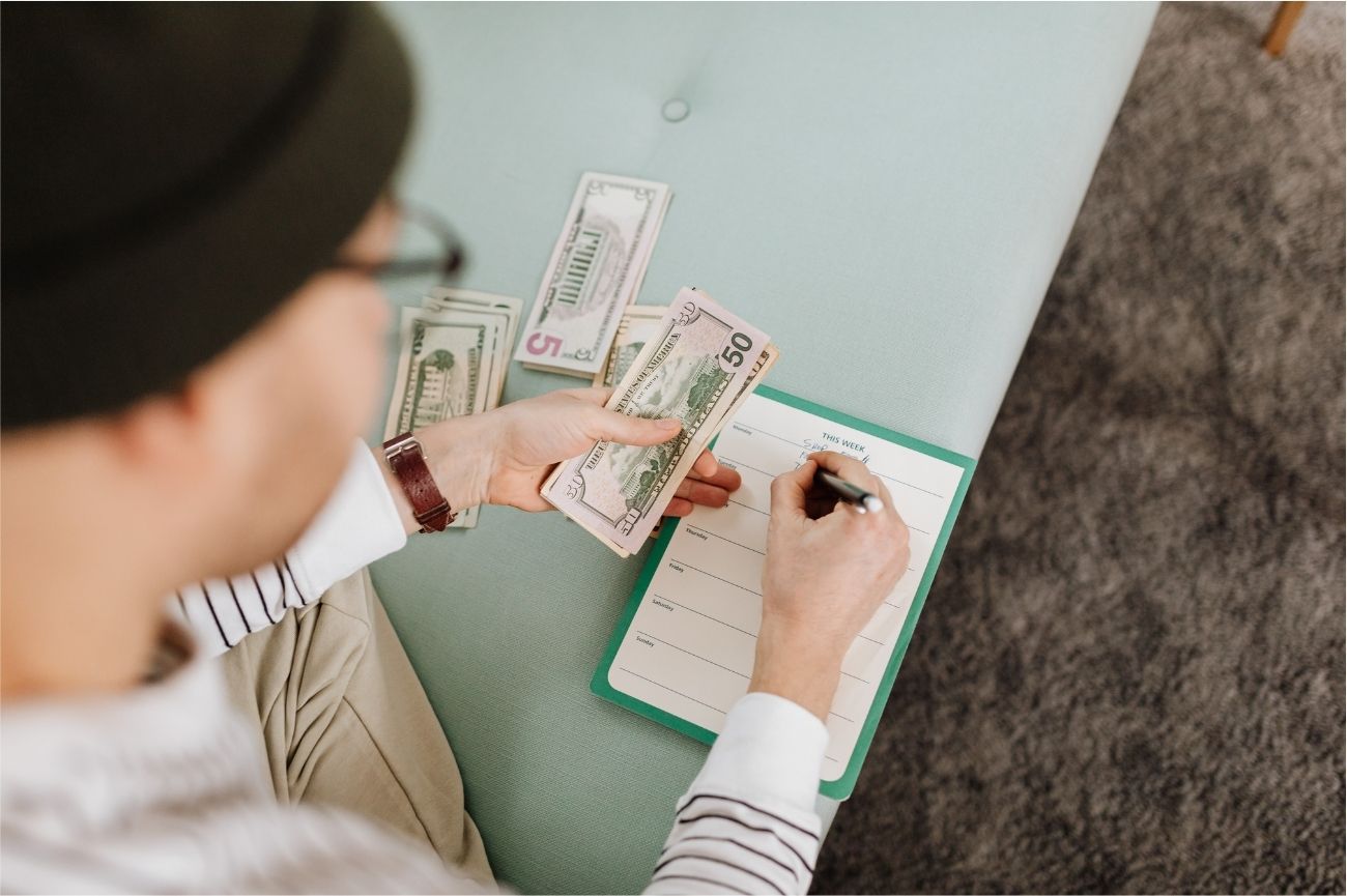 Man writing in a budget planner journal while practicing loud budgeting and setting financial goals